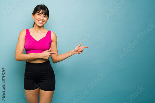 Sporty fitness trainer pointing to copy space