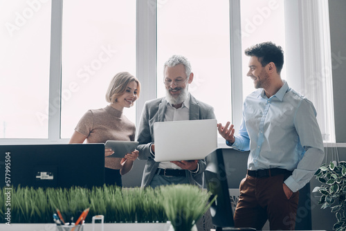 Εκτύπωση καμβά Three happy business people having discussion during the quick meeting in office