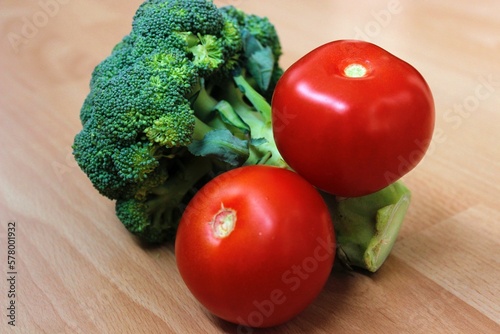 Broccoli and two tomatoes on a wooden background. Healthy and fresh vegetables. Organic food.