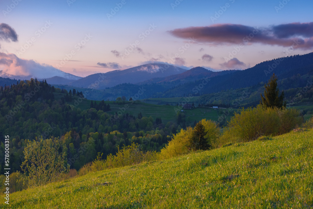 sunset over the rural mountain valley. the rolling hills and mountain peaks provide a stunning backdrop