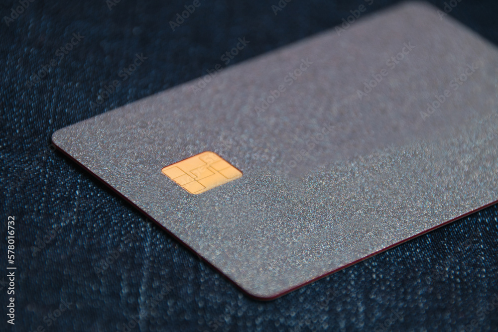 Bank card with a modern chip on a denim background. Concept of safe online operations with bank accounts and protection of bank cards from fraudsters Bank card with a modern chip on a denim background. Concept of safe online operations with bank accounts and protection of bank cards from fraudsters