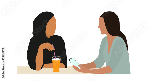 Portrait of two young women talking sitting at table. The concept of friendship or business between people of different religions.