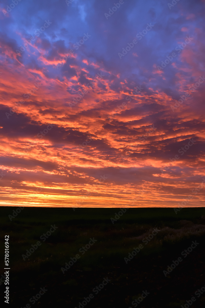 The photo shows a breathtaking red sunset, with the sky painted in shades of crimson, orange, and gold. The sun is just visible on the horizon, casting a warm glow over the landscape below.