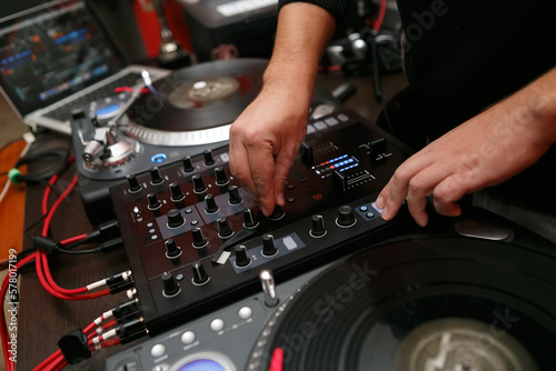 Hip hop DJ mixing vinyl records on turn table in close up. Professional disc jockey plays music set with sound mixer and turntables