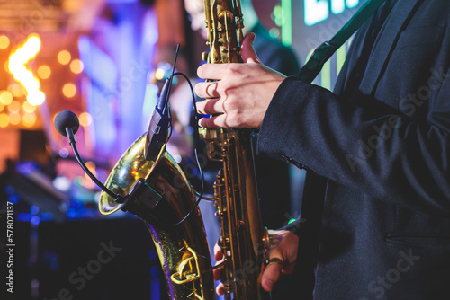 Concert view of saxophonist, a golden saxophone, sax player with vocalist and musical band during jazz orchestra show performing music on a stage in the scene lights