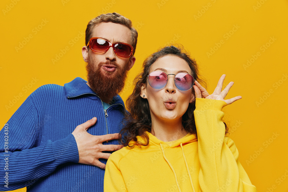 Obraz premium Man and woman couple smiling cheerfully and crooked with glasses, on yellow background, symbols signs and hand gestures, family shoot, newlyweds.
