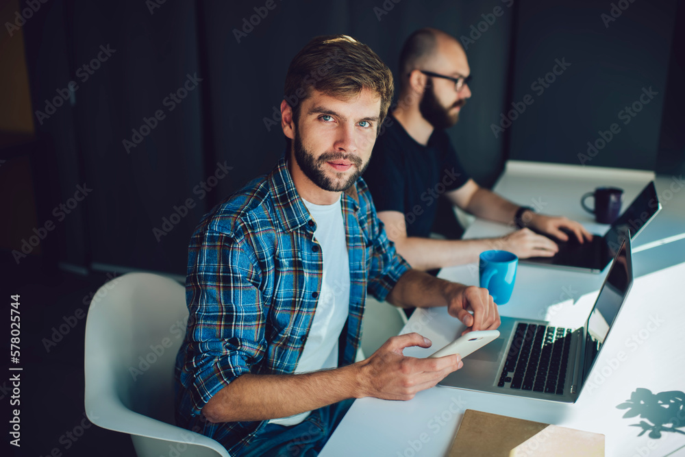 Male freelancer typing message on mobile phone in office Male freelancer typing message on mobile phone in office