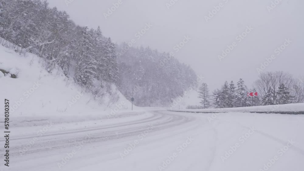 Extensive snowfall moving across the countryside. Poor visibility and barely seen roadway due to heavy snow. Big snowflakes are falling and cover empty road. Extensive snowfall moving across the countryside. Poor visibility and barely seen roadway due to heavy snow. Big snowflakes are falling and cover empty road.