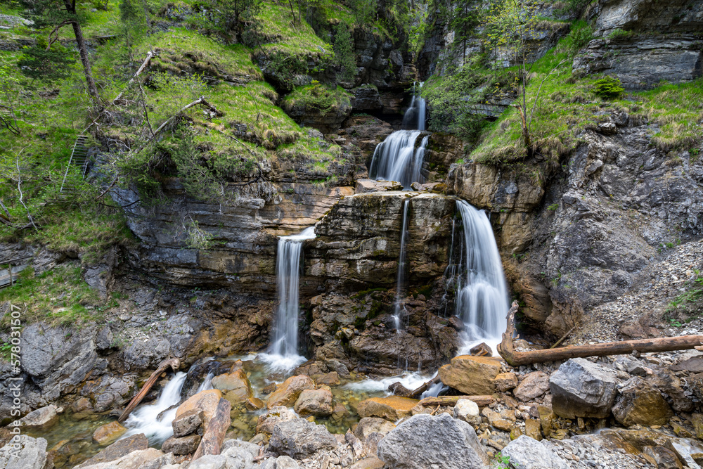Wasserfall der sich teilt über Felsen im Wald mit grünen Bäumen und Moos. Kuhflucht Wasserfälle bei Farchant in Bayern. - obrazy, fototapety, plakaty 