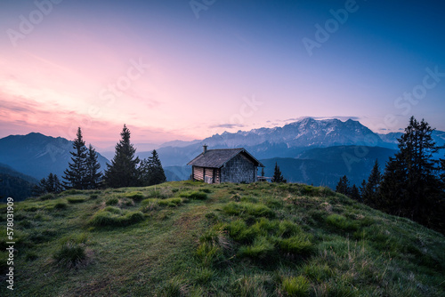 Hütte auf Almwiese in den Vergen mit Pfad oder Weg und Bergpanorama. photo