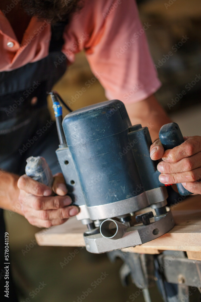 Carpenter using working tools while working on a wood in carpentry workshop