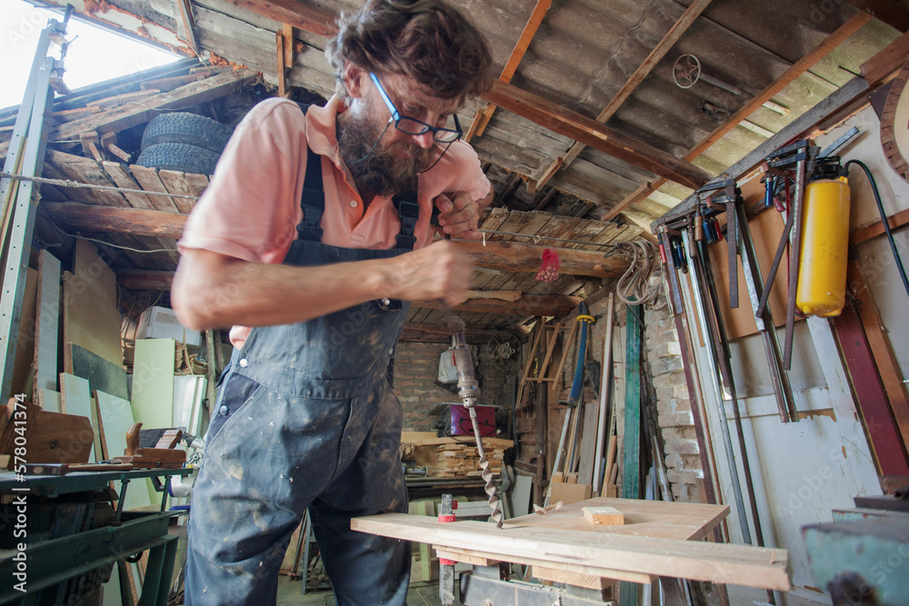 Carpenter using working tools while working on a wood in carpentry workshop Carpenter using working tools while working on a wood in carpentry workshop