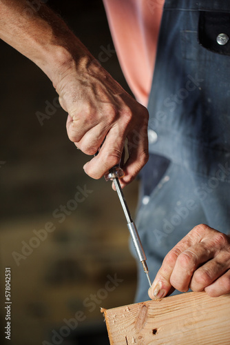 Carpenter using working tools while working on a wood in carpentry workshop