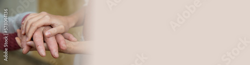 The hands of a young girl hold the bitches of her elderly grandmother. The concept of love and care for the elderly, respect within the family and acceptance of old age. Banner.