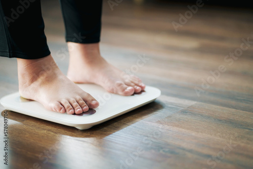 Woman feet standing on weigh scales, diet concept..