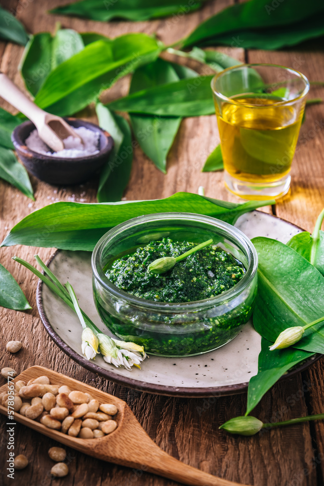Homemade wild garlic pesto in a glass bowl on wooden background, decorated with leaves, parmesan cheese and olive oil, vertical Homemade wild garlic pesto in a glass bowl on wooden background, decorated with leaves, parmesan cheese and olive oil, vertical