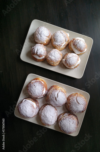 Plates with traditional homemade semlor with whipped cream | fastlagsbulle, fettisdag | dessert windbags, cream puffs | vegan semla, swedish eclair photo