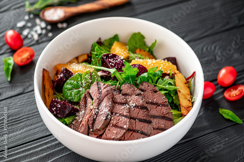 Salad with roast beef and caramelized beets with orange fillet, potatoes, parmesan, salad mix and olive oil