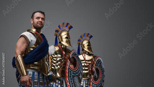 Studio shot of handsome three warriors from ancient greece dressed in bronze plate armors.
