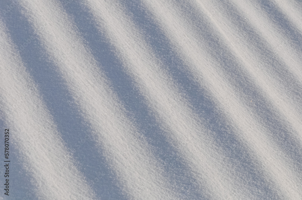 Snow lies in waves in a cold snowy winter, the play of light in straight lines