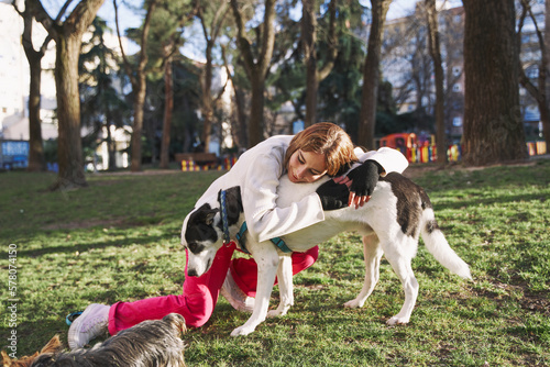 Caucasian woman hugging her dog on a walk in the park.