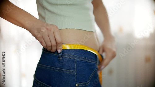 woman measures her waist after losing weight