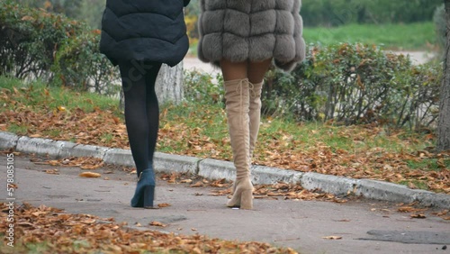 Sexy legs with high heels goes in a big city park. Sexy erotic womans.Escort, paid sex or prostitution. Roamntic womans walking on boulvard. Attractive girls in short dress at autumn season.