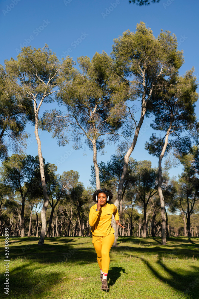 A girl in a yellow tracksuit jogs in the park