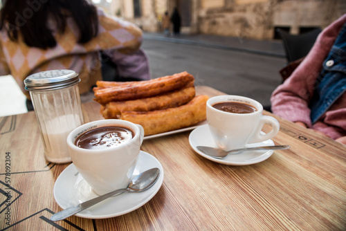 Tray of churros and two cups of chocolate on the terrace table, ready to eat the traditional Spanish churros in the bar.