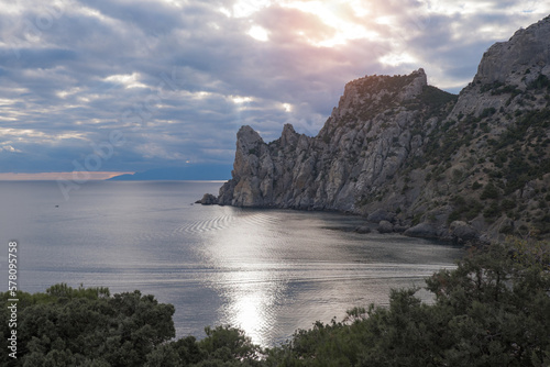 stone road in the mountains against the backdrop of a calm sea. Rocks and trees at sunset, blue sky. Evening relaxation, relaxation, meditation. Wallpaper and screensaver. High quality photo