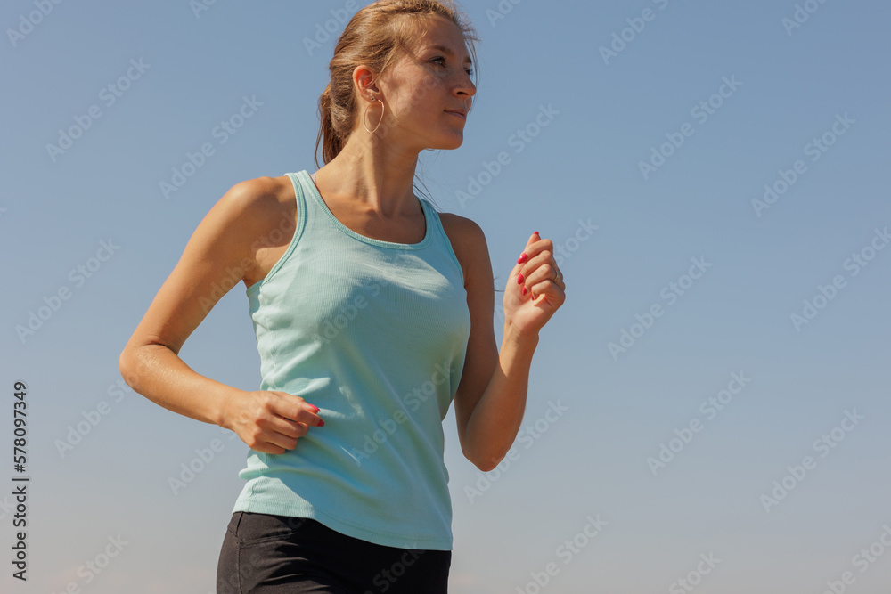 portrait of sporty woman jogging in morning on ocean. young confident woman runs to marathon and takes care of physical and mental condition. healthy lifestyle. fitness and yoga