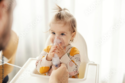 Obraz na płótnie Portrait of a baby girl inhaling medicine on nebulizer by her own