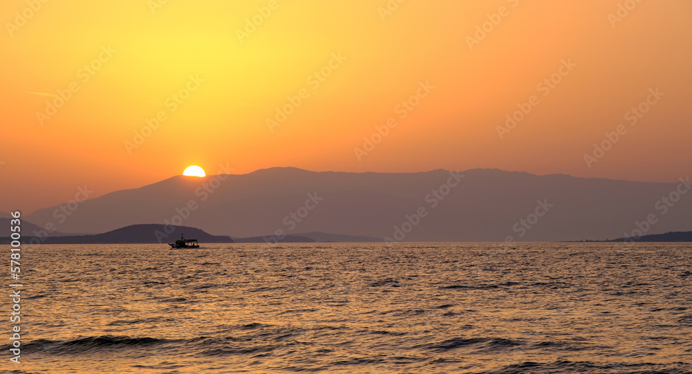 Sea and sunset over mountain landscape. Minimalist concept can be used as large printed canvas, website banner, social media post. Blank copy space for advertising texts.