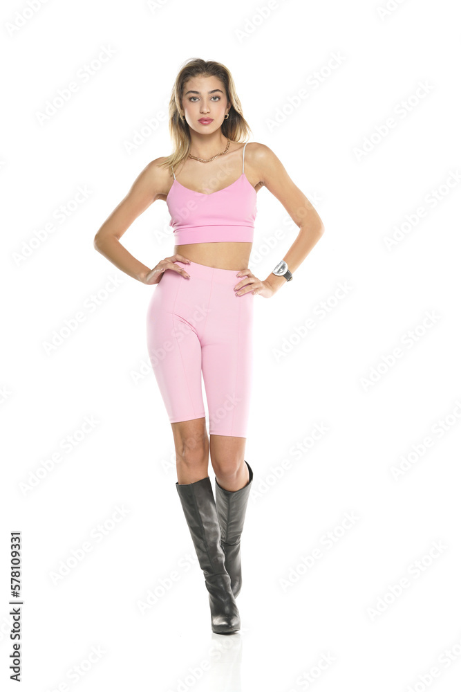a young woman in pink short leggings and top, and black leather boots walking on a white background a young woman in pink short leggings and top, and black leather boots walking on a white background