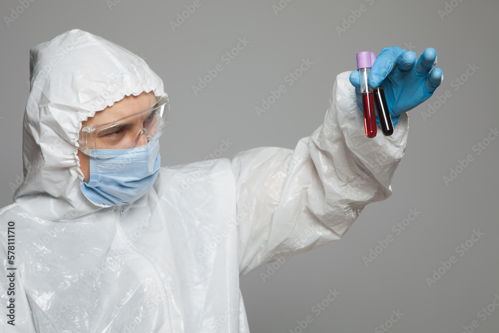 Scientific virologist. Biologist in protective suit and blue gloves holds test tubes with blood. Test tube with viruses concept. Virus University employee. Scientific virologist. Biologist in protective suit and blue gloves holds test tubes with blood. Test tube with viruses concept. Virus University employee.