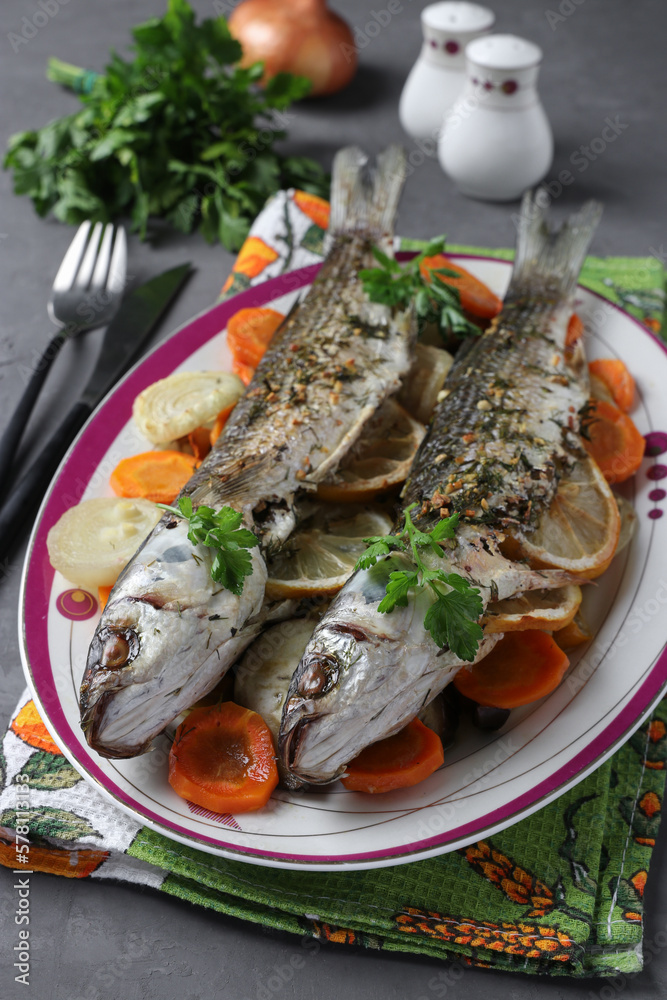Mullet baked with vegetables, spices and lemon served on a plate