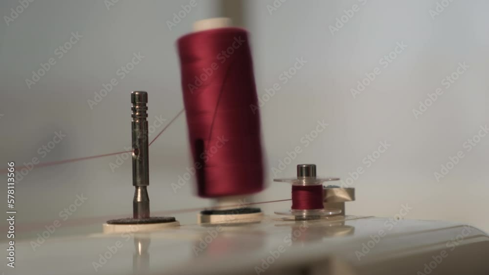 Thread is wound on bobbin of sewing machine closeup. Process of