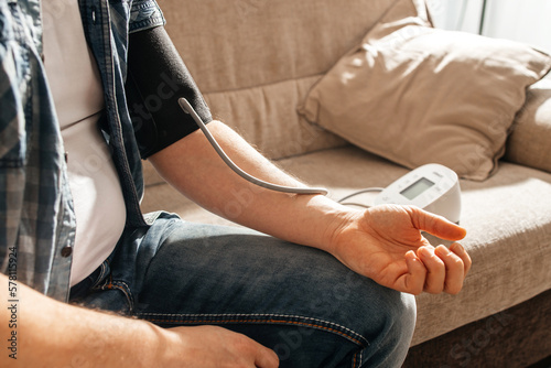 Quadro su tela A man measures his blood pressure at home using a tanrometer and a measuring cuff