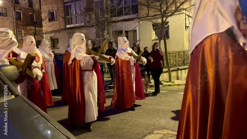 Soria, Spain - April 11, 2022: Video of Holy Week procession of hooded people down the street carrying the Christ on Holy Monday photo