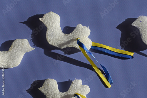 Paper doves of peace with wings made of yellow blue ribbons of the Ukrainian flag.Blue background.Top view, flat lay.