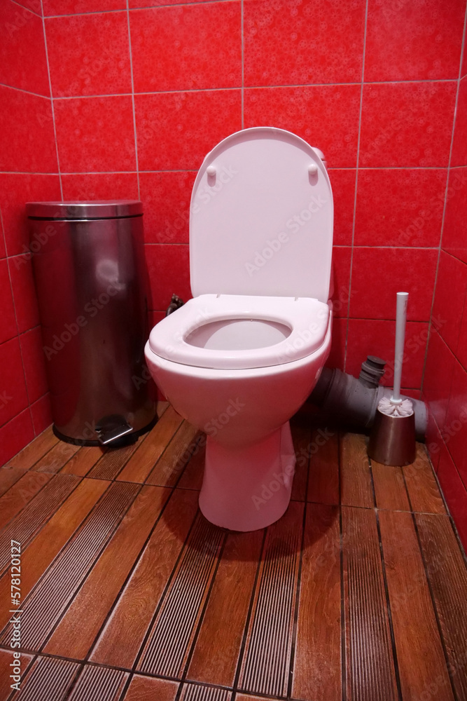 Toilet room with toilet bowl, wastebasket, toilet brush and red wall tiles Toilet room with toilet bowl, wastebasket, toilet brush and red wall tiles