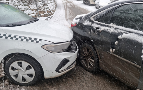 the collision of a white taxi and a black car due to ice.  © andrey