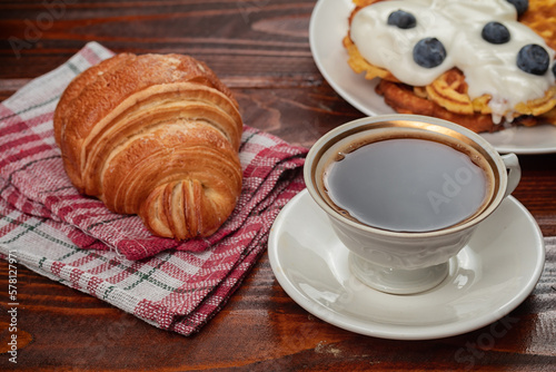 Fototapeta Naklejka Na Ścianę i Meble -  fresh baked croissant and cup of coffee on wooden table.