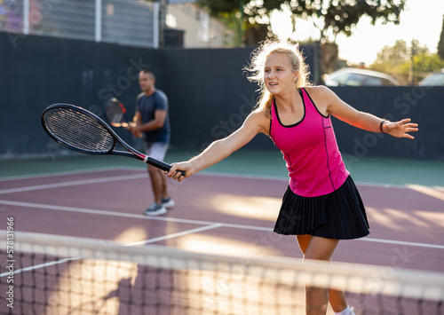 Sports active woman and her male partner playing tennis on court together during friendly match outdoor © JackF