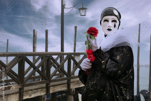 VENICE, Italy - February 17th 2023: Pierrot pierrot with rose in hand in the background Venice lagoon, Carnival mask. photo