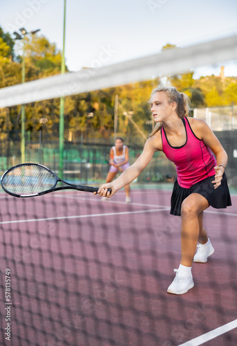 Sporty woman plays tennis. View through tennis net