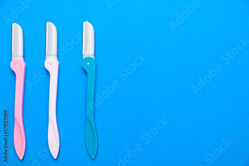 women s razors with plastic handles of different colors on a blue background. Space for text.
