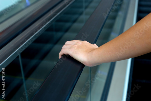Hand holding escalator handrail in shopping mall or building