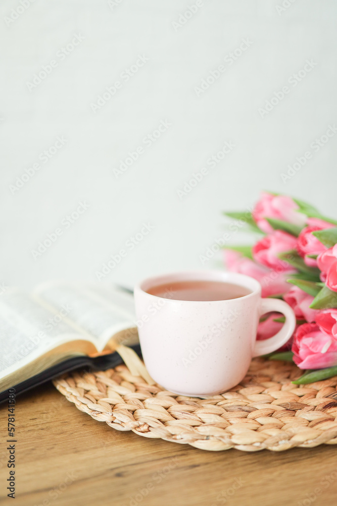 Open bible with tulip flowers and a cup of tea on light wood Open bible with tulip flowers and a cup of tea on light wood