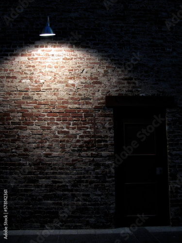 Brick wall, single light, and door at night